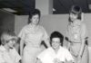 Altes Foto von vier Frauen in Schwesternkittel, die sich gemeinsam Unterlagen ansehen