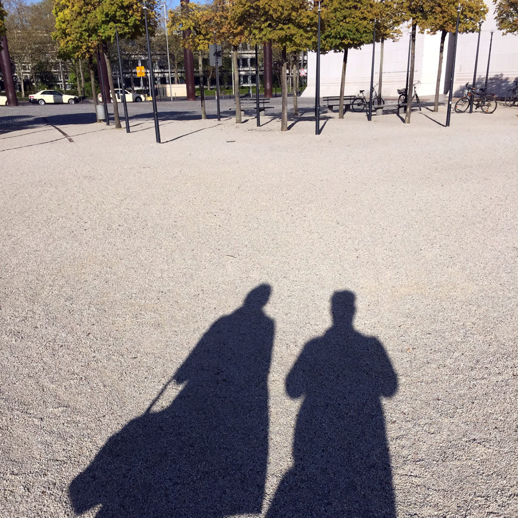 Schatten einer Frau und eines Mannes auf einer großen Kiesfläche