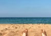 Strand, Meer und zwei teilweise mit Sand bedeckte Füße