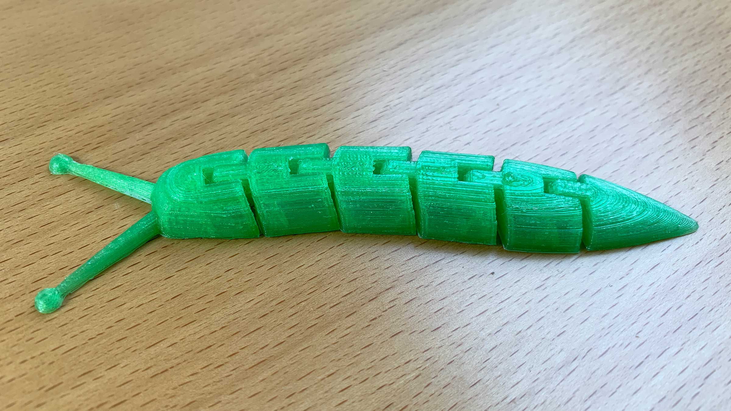 Eine grüne 3D-Schnecke (ohne Haus, dafür mit sechs beweglichen Gliedern und langen Fühlern)