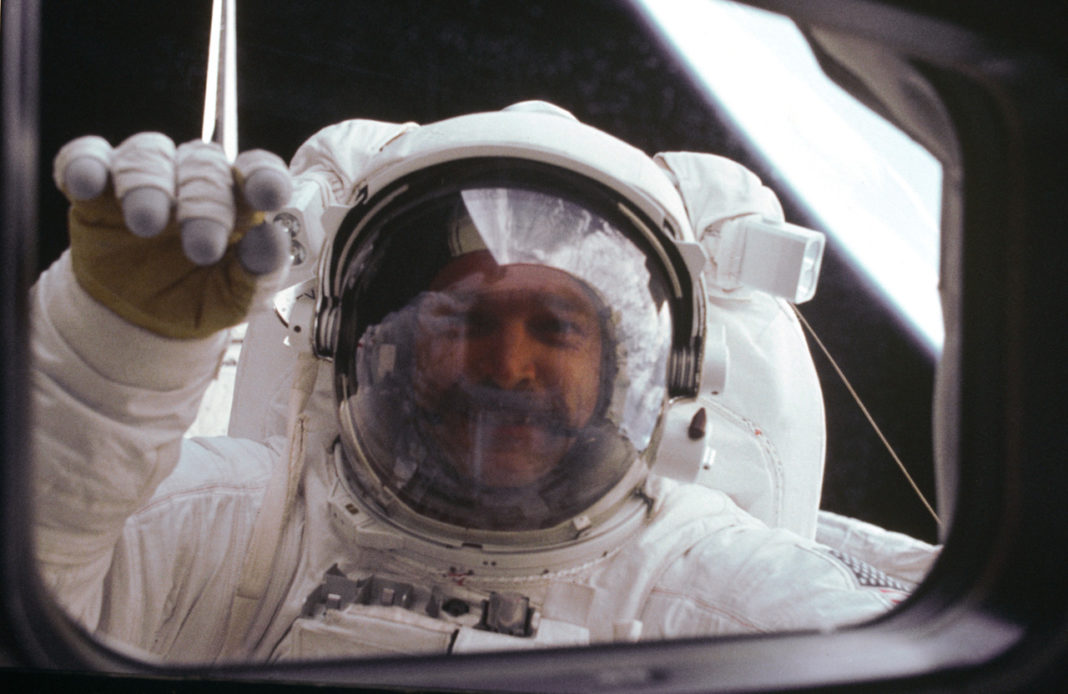Ein Astronaut im Weltall klopft von außen an das Fenster.