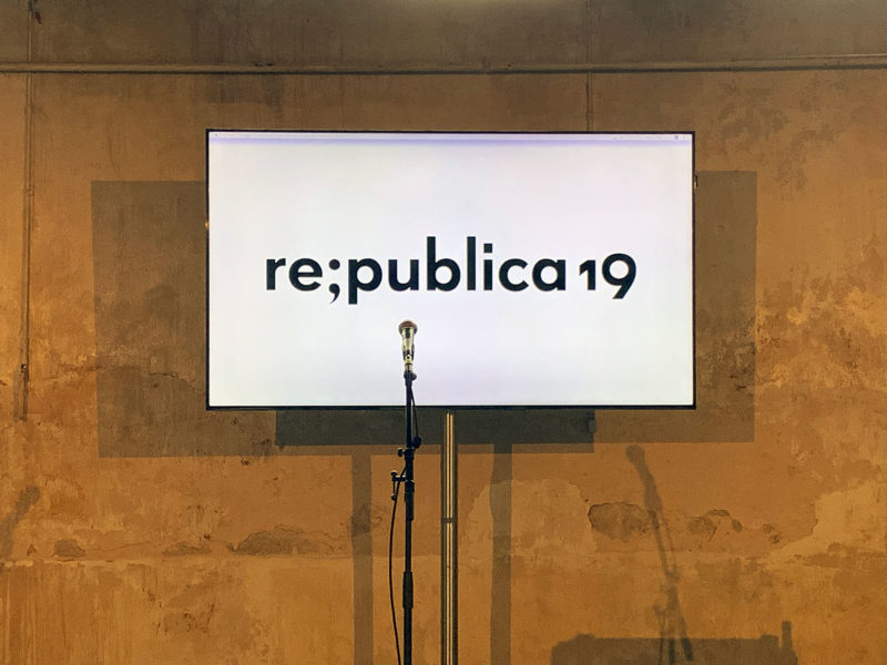 Ein Bildschirm an der Wand mit dem Logo der Republica, davor ein Mikrofon auf einem Ständer.