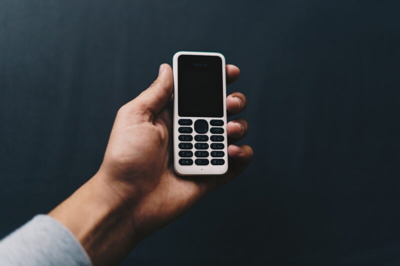 Eine Hand, die ein altes Tasten-Handy hält