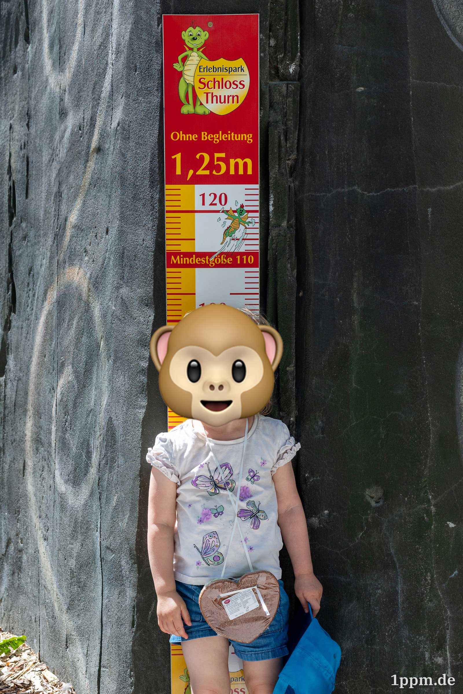 Ein Kind steht vor einem Maßstab, das die erlaubte Größe anzeigt. 110 Zentimeter ist das Mindestmaß, das Kind ist noch etwa acht Zentimeter zu klein dafür. 1,25 Meter wäre nötig, um ohne Begleitung das Fahrgeschäft nutzen zu können.