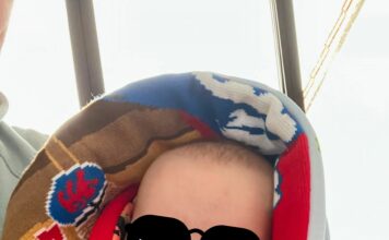 Ein kleiner Junge ist in einen Schal gewickelt. Auf seine Augen wurde eine Sonnenbrille retuschiert.