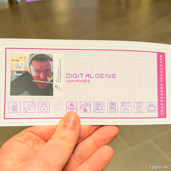 Ich halte einen Zettel in der Hand mit einem Foto von mir und der Aufschrift „Digitalgenie“.