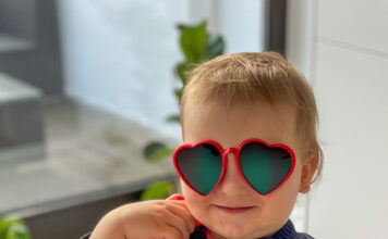 Klein-Tyler am Spielzeugtelefon, er hält den Hörer in der Hand und blickt freudig in die Kamera. Auf seine Augen wurde eine auffällige Herzchen-Sonnenbrille retuschiert.