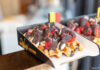 Eine dicke belgische Waffel mit einer kleinen belgischen Flagge. Die Waffel ist reichlich mit Bannenscheinen, Erdbeeren und einer dicken Schokoladenschicht garniert.