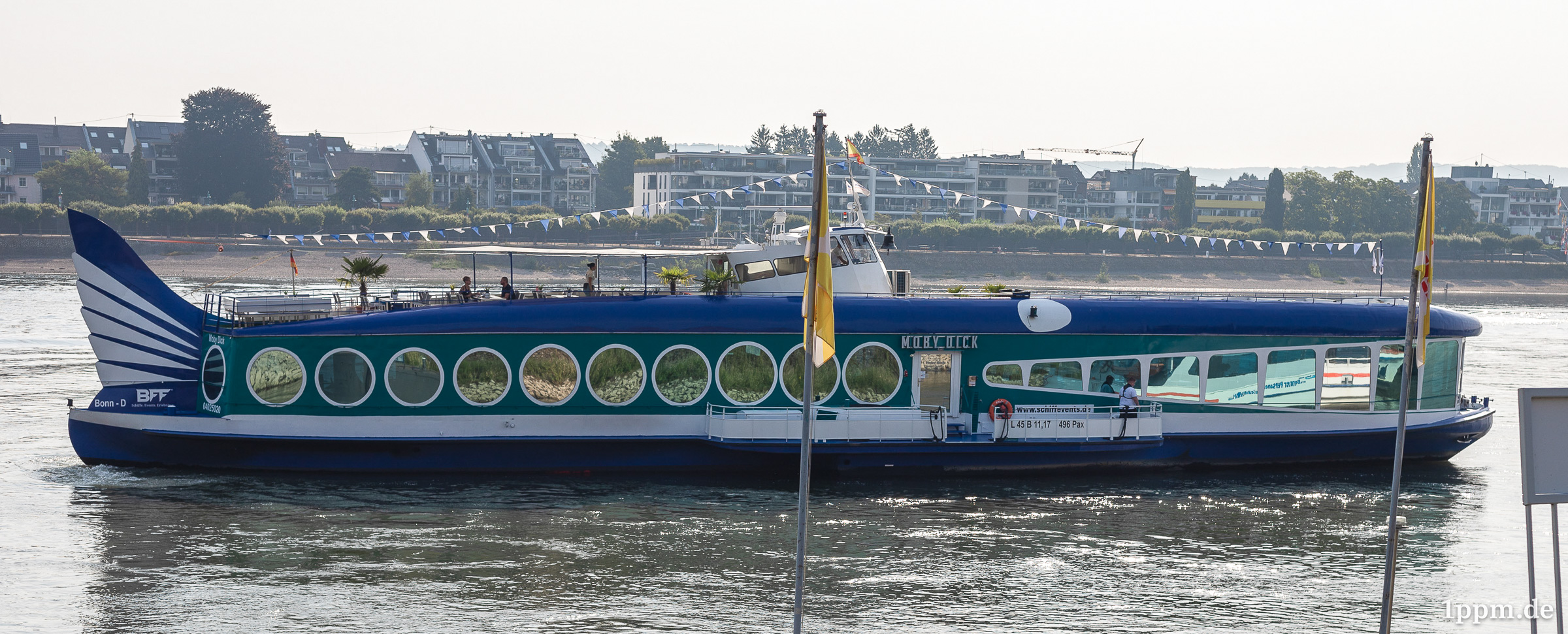 Ein blaues Schiff mit Schwanzflosse, Auge und Fenstern, die wie ein Maul aussehen.