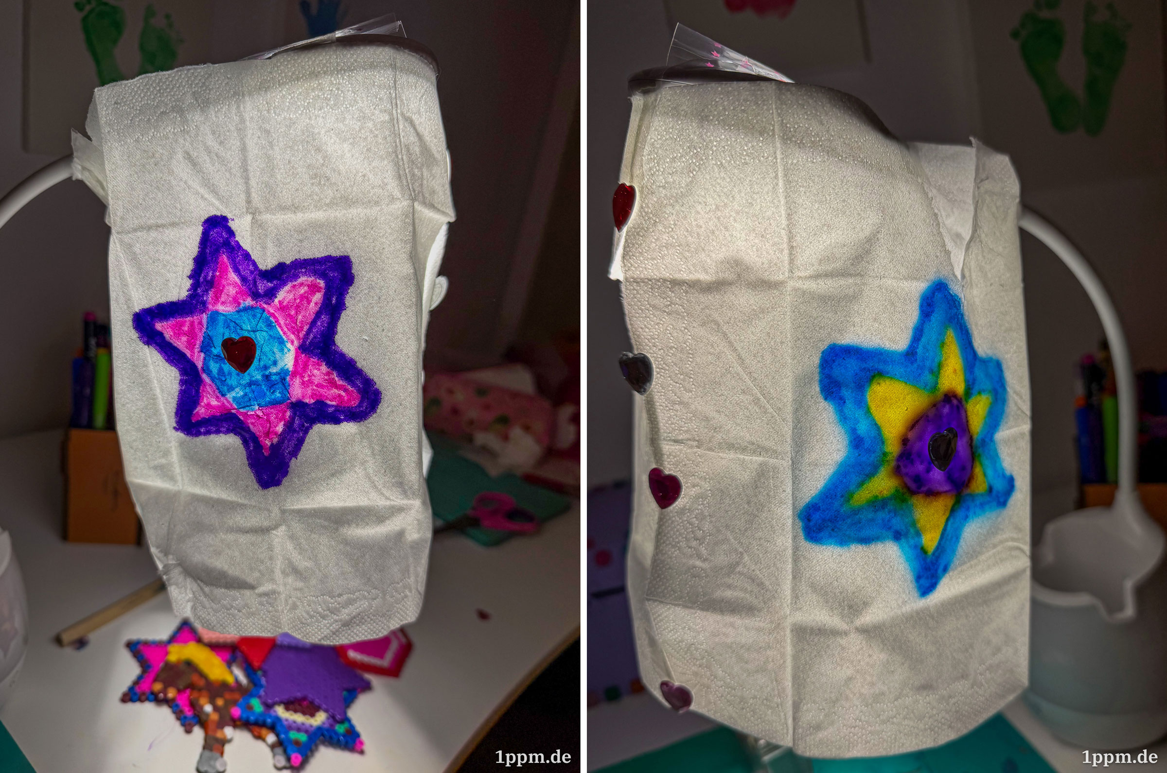 Zwei Seiten des „Lampenschirms“ bzw. der „Laterne“. Auf der einen Seite ist ein sechszackiger Stern mit lila Rand und rosa-blauem Innenleben. Auf der anderen Seite ein blau umrandeter Stern mit gelb-lila innen. Auf beiden klebt ein kleines Herz in der Mitte. Beide Taschentücher werden mit mehreren Klebeherzen zusammengehalten.