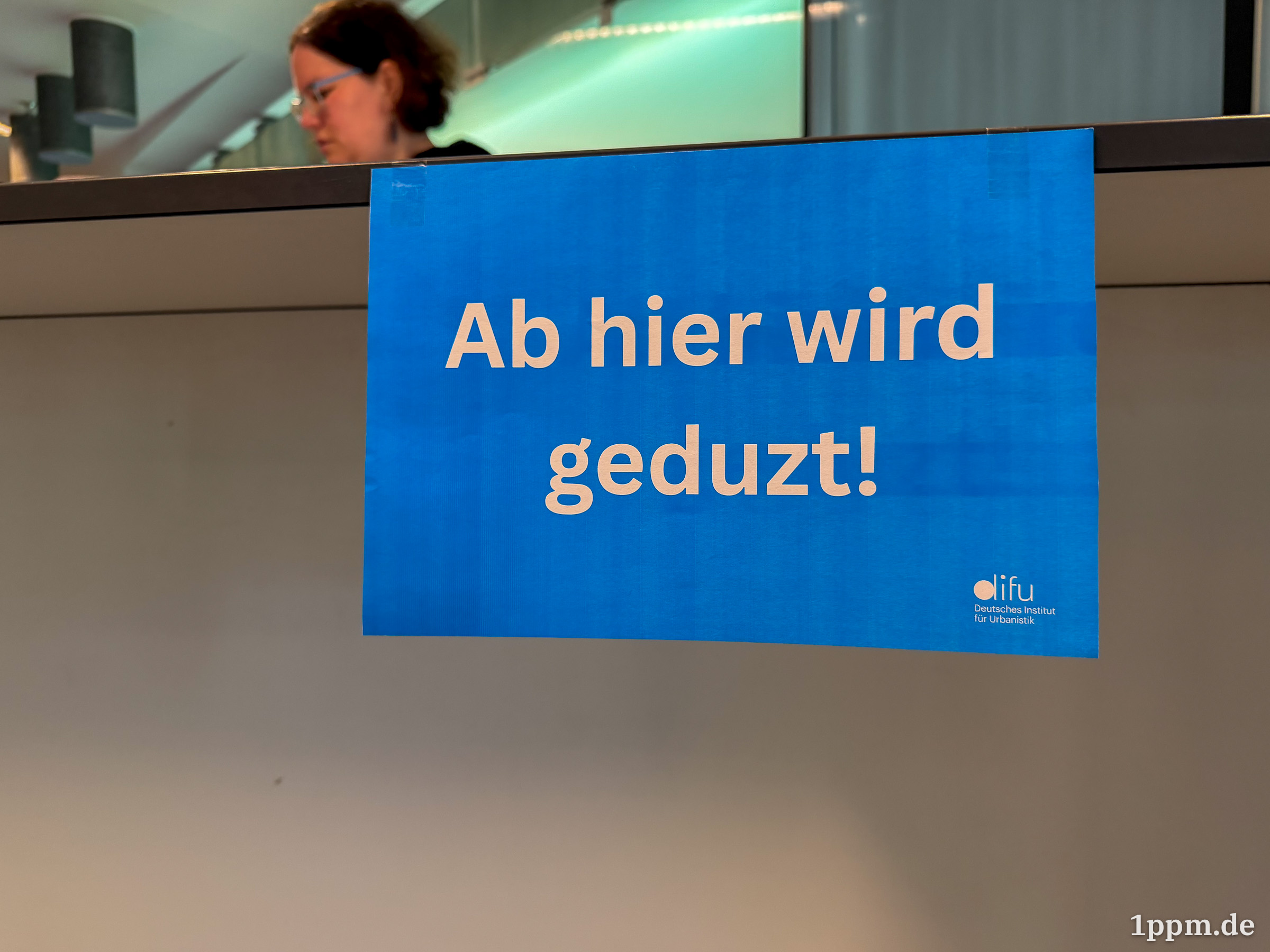 Blaues Schild mit der Aufschrift 'Ab hier wird geduzt!' und kleinem Logo des Deutschen Instituts für Urbanistik